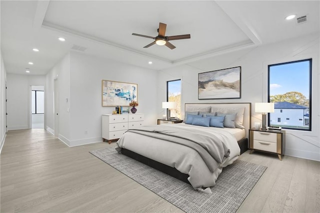 bedroom featuring ceiling fan, light hardwood / wood-style flooring, and a raised ceiling