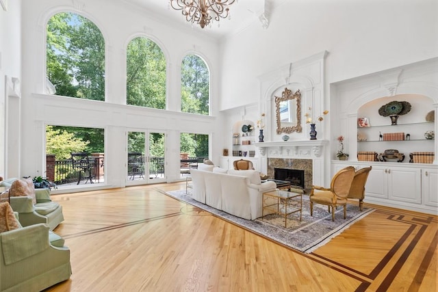 living room featuring a healthy amount of sunlight, a towering ceiling, hardwood / wood-style floors, and a fireplace