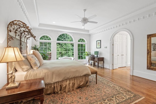 bedroom with ceiling fan, ornamental molding, a tray ceiling, and hardwood / wood-style floors