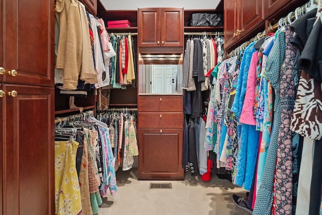 walk in closet with light colored carpet