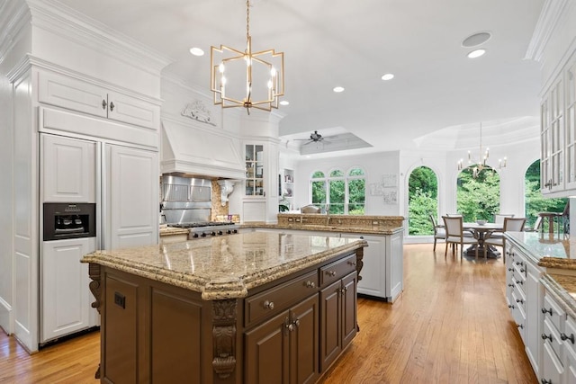 kitchen with dark brown cabinets, pendant lighting, ceiling fan with notable chandelier, white cabinetry, and a kitchen island