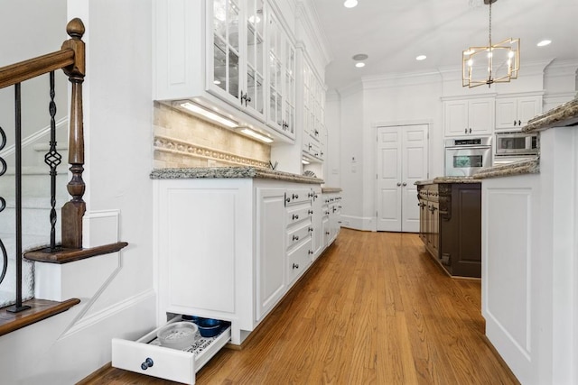 kitchen featuring white cabinets, light hardwood / wood-style flooring, stainless steel appliances, decorative backsplash, and decorative light fixtures