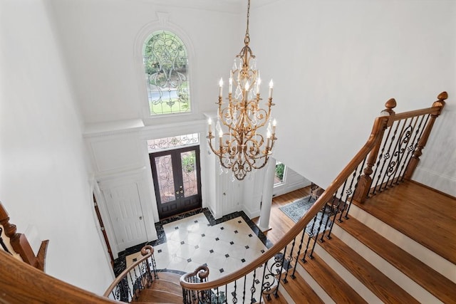 foyer featuring hardwood / wood-style floors, an inviting chandelier, and french doors