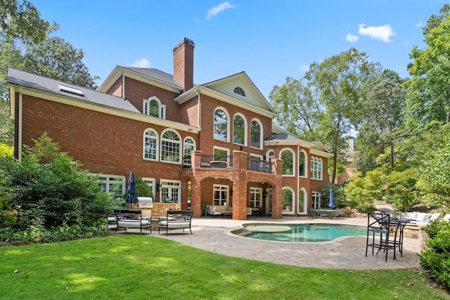 rear view of house with a balcony, a yard, and a patio area