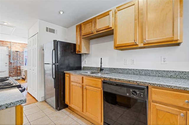 kitchen with light stone countertops, sink, brick wall, light tile patterned floors, and black appliances