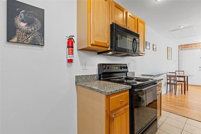 kitchen featuring light hardwood / wood-style floors, dark stone countertops, and black appliances