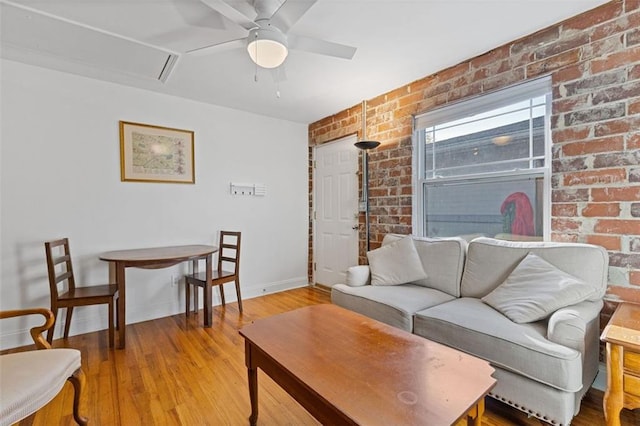 living room with ceiling fan, wood-type flooring, and brick wall