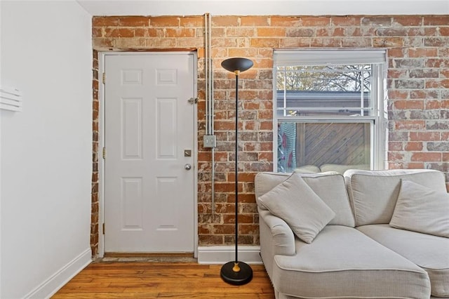 sitting room with hardwood / wood-style floors and brick wall