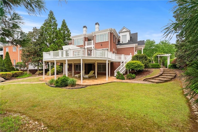 rear view of house featuring stairs, brick siding, a deck, a patio area, and a yard