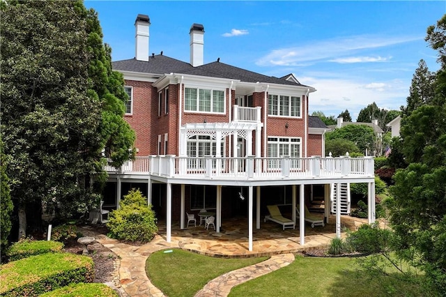 rear view of house featuring a chimney, a wooden deck, stairway, brick siding, and a patio