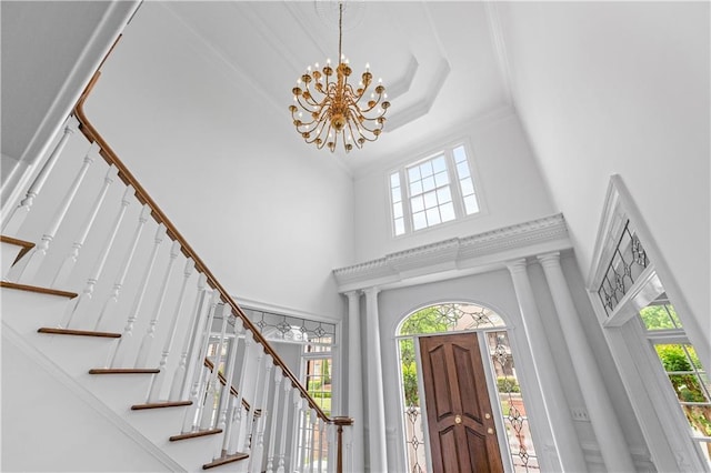 entrance foyer featuring stairs, ornamental molding, a healthy amount of sunlight, and a towering ceiling