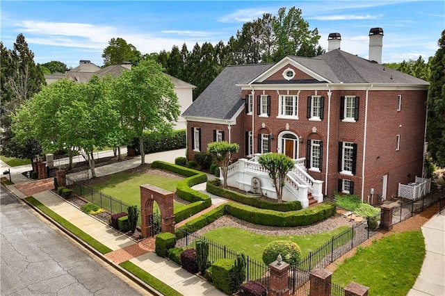 view of front of property featuring fence private yard, brick siding, a chimney, and a front yard