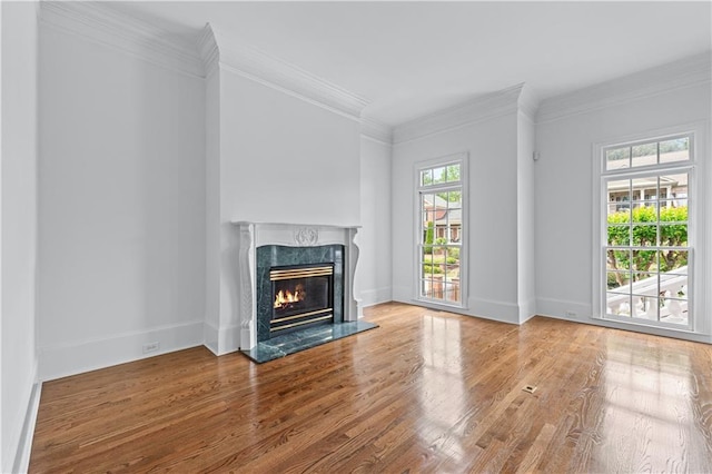 unfurnished living room with a high end fireplace, baseboards, ornamental molding, and wood finished floors