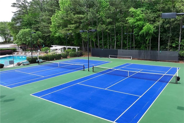 view of tennis court featuring fence and community basketball court