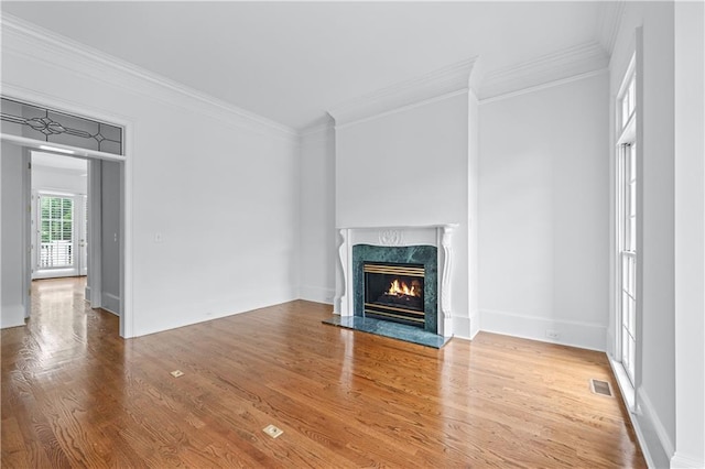 unfurnished living room featuring visible vents, crown molding, wood finished floors, and a premium fireplace