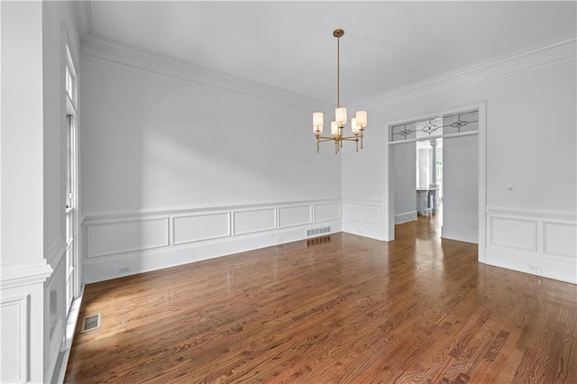 unfurnished dining area featuring a notable chandelier, a decorative wall, a wainscoted wall, visible vents, and ornamental molding