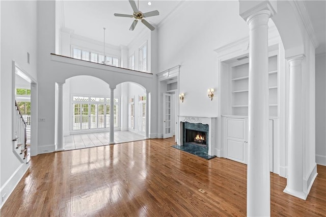 unfurnished living room featuring crown molding, a ceiling fan, and wood finished floors