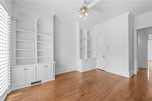 unfurnished living room with baseboards, ornamental molding, a ceiling fan, and built in shelves
