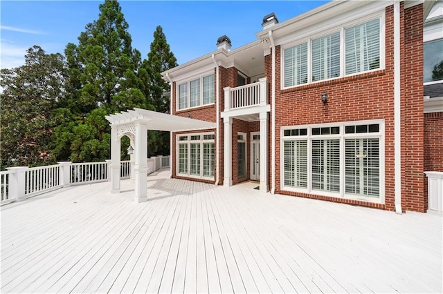 back of property with brick siding, a chimney, a pergola, and a deck