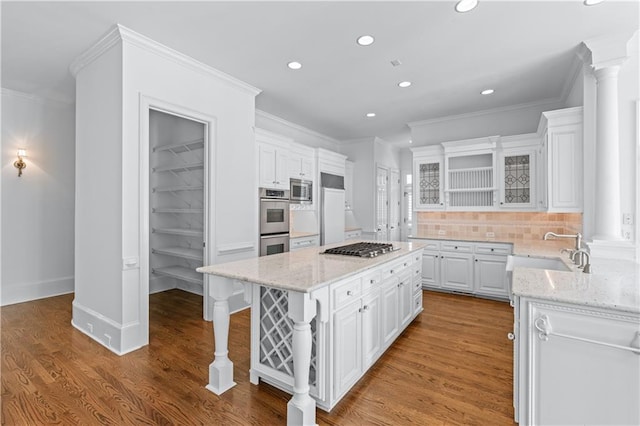 kitchen with built in appliances, recessed lighting, a center island, white cabinetry, and a sink