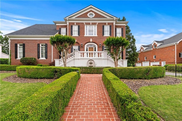 colonial-style house with brick siding, a front lawn, and fence