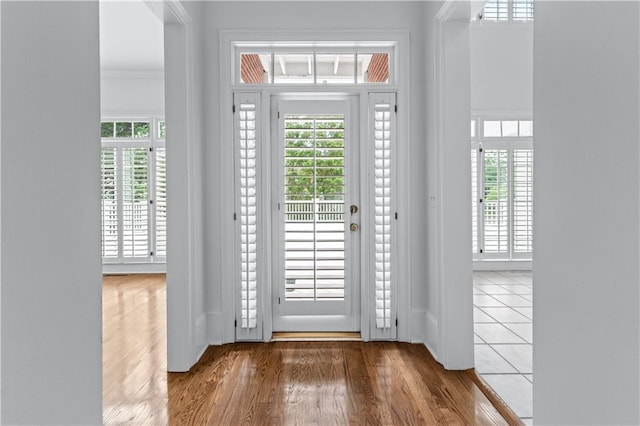 entryway with crown molding, baseboards, and wood finished floors
