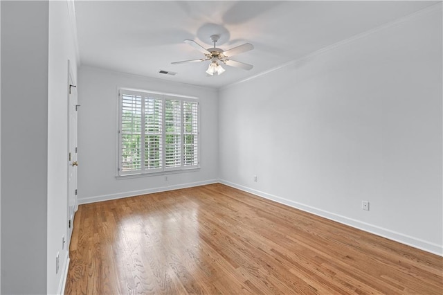 empty room featuring crown molding, baseboards, a ceiling fan, and visible vents