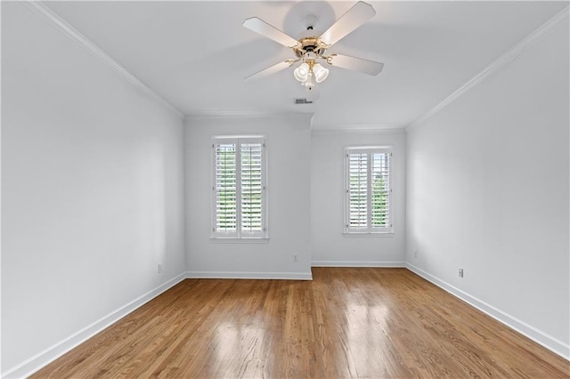 spare room featuring crown molding, baseboards, and wood finished floors