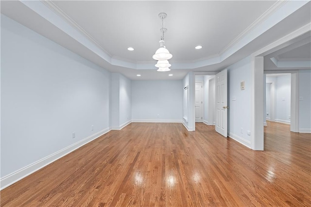 interior space featuring ornamental molding, a tray ceiling, wood finished floors, and a chandelier