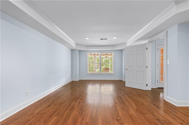 empty room featuring baseboards, a tray ceiling, and wood finished floors