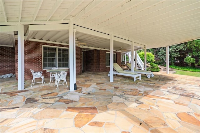 view of patio with a ceiling fan and stairs