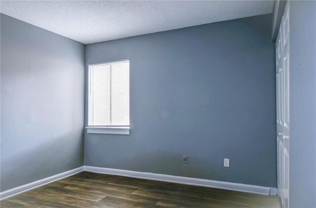 unfurnished room featuring a textured ceiling and dark hardwood / wood-style floors