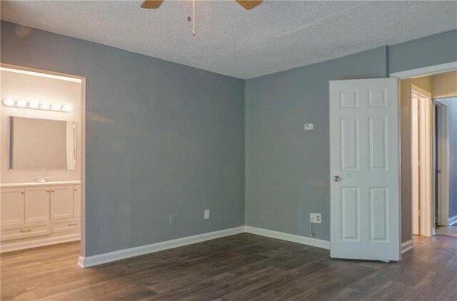 unfurnished bedroom featuring a textured ceiling, dark wood-type flooring, and ensuite bath