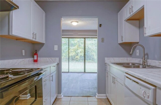 kitchen with light stone countertops, sink, light tile patterned floors, dishwasher, and white cabinets