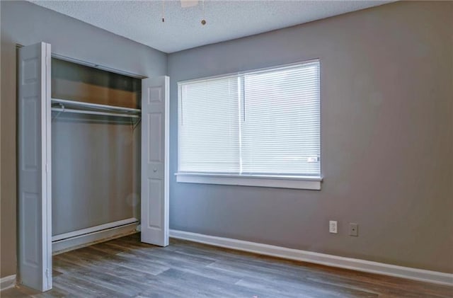 unfurnished bedroom featuring a textured ceiling, ceiling fan, a closet, and dark hardwood / wood-style floors