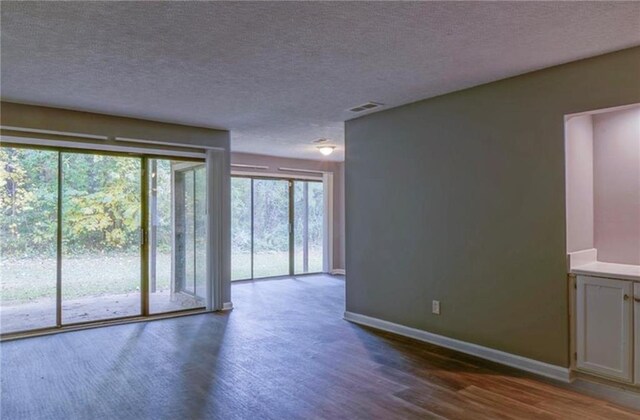 unfurnished room with dark hardwood / wood-style floors and a textured ceiling