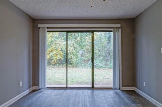 doorway with a textured ceiling, dark wood-type flooring, and a wealth of natural light