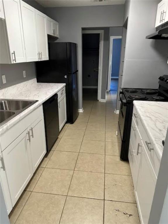 kitchen featuring black appliances, light tile patterned flooring, light stone countertops, and white cabinetry