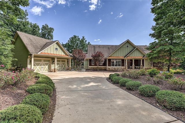 craftsman-style home featuring a garage, a shingled roof, driveway, stone siding, and board and batten siding