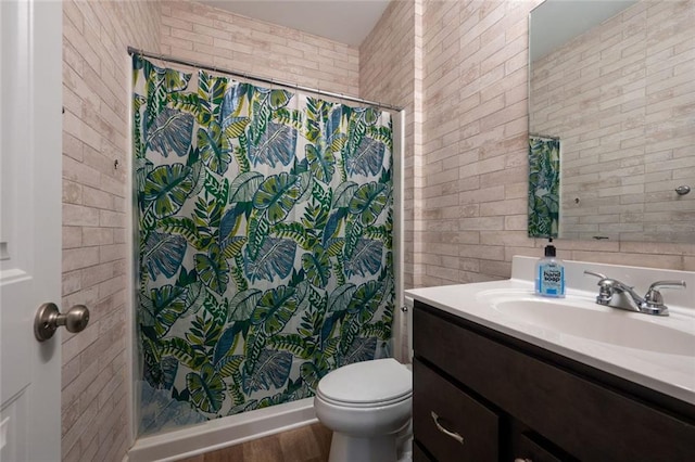 bathroom with vanity, a shower with shower curtain, toilet, wood-type flooring, and brick wall