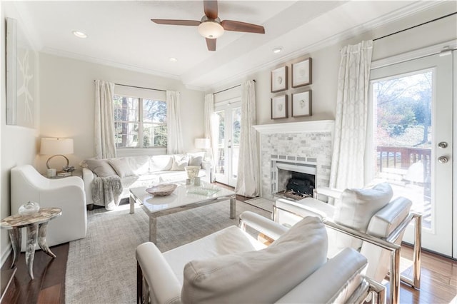 living area with ceiling fan, wood finished floors, crown molding, a fireplace, and recessed lighting