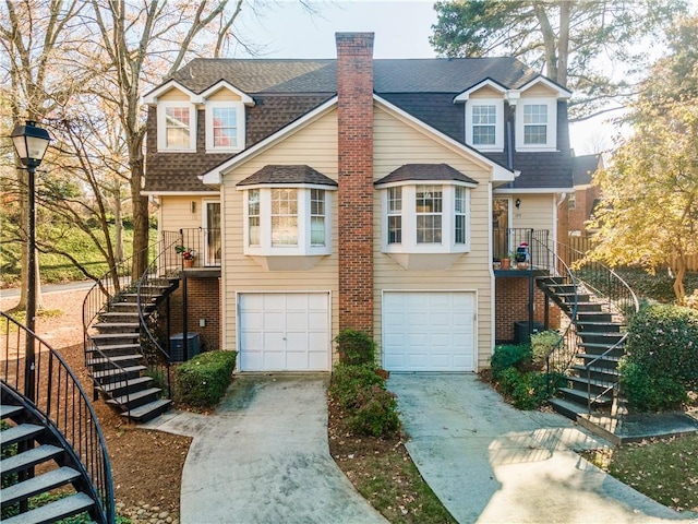 view of front of house with concrete driveway, roof with shingles, and stairs