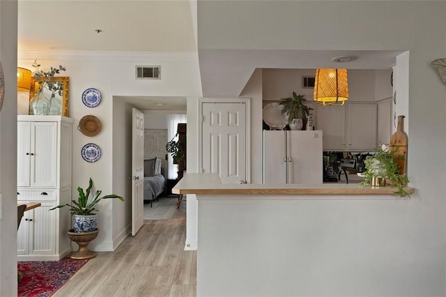 3777 Peachtree Rd NE Unit 1227, Brookhaven, GA 30319 - kitchen featuring freestanding refrigerator, light wood-style floors, a peninsula, light countertops, and ornamental molding