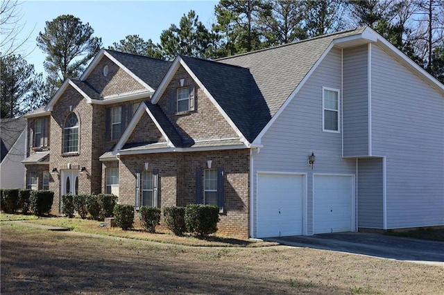 view of front facade with an attached garage, driveway, a shingled roof, and brick siding