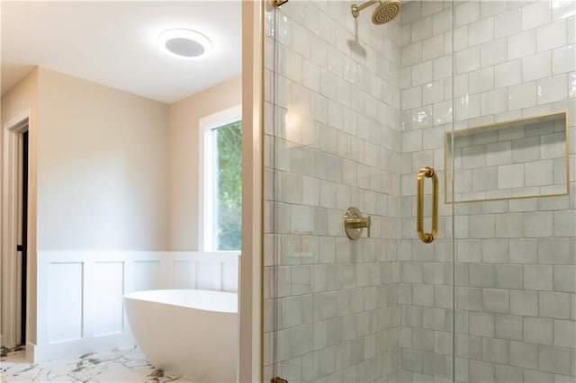 45 Driskell Ave, Mableton, GA 30126 - bathroom featuring a stall shower, a freestanding tub, marble look tiles, a wainscoted wall, and a decorative wall
