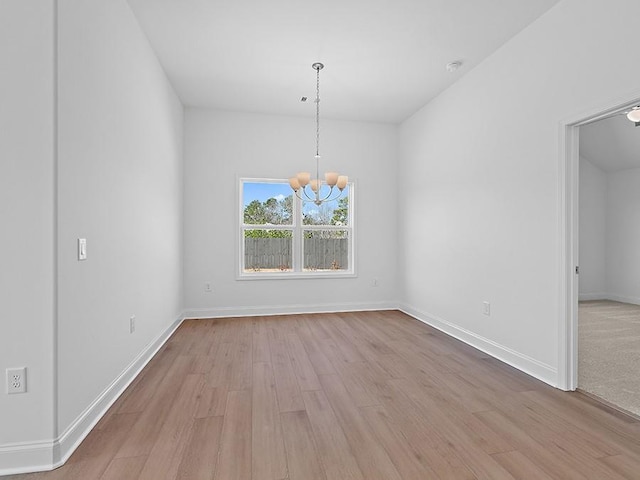 unfurnished dining area with baseboards, a notable chandelier, and wood finished floors