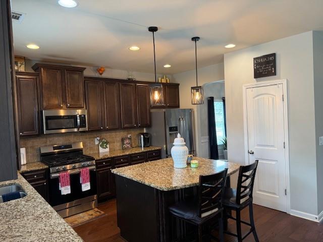 558 Hideaway Dr, Jonesboro, GA 30238 - kitchen featuring appliances with stainless steel finishes, dark brown cabinets, decorative backsplash, light stone countertops, and dark wood-style floors
