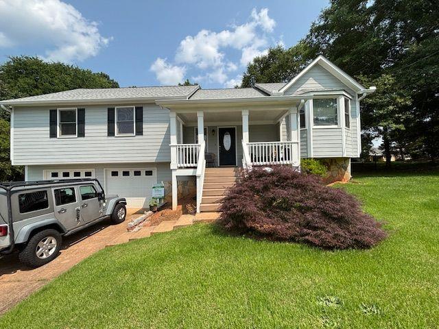 403 Hickory Walk, Woodstock, GA 30188 - view of front of house featuring covered porch, a front yard, driveway, an attached garage, and stairway