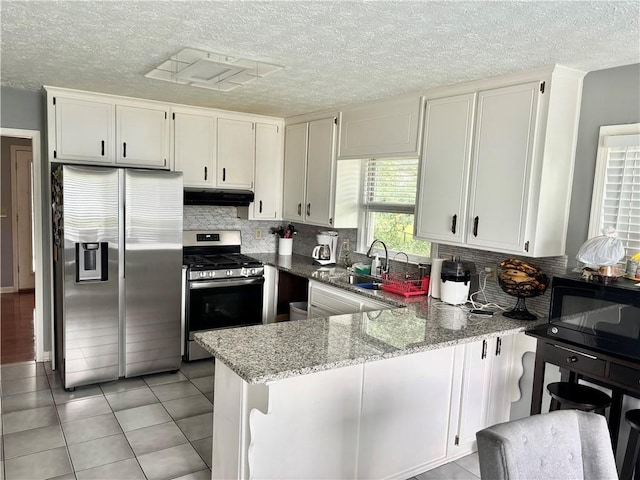 403 Hickory Walk, Woodstock, GA 30188 - kitchen with stainless steel appliances, a sink, a peninsula, under cabinet range hood, and light stone counters