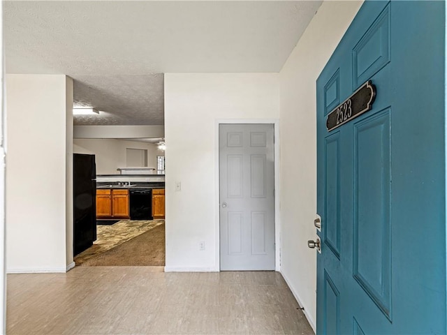 entrance foyer featuring light wood-type flooring, a textured ceiling, and baseboards